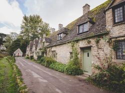 Row of charming stone cottages with mossy roofs and climbing plants in a countryside village.