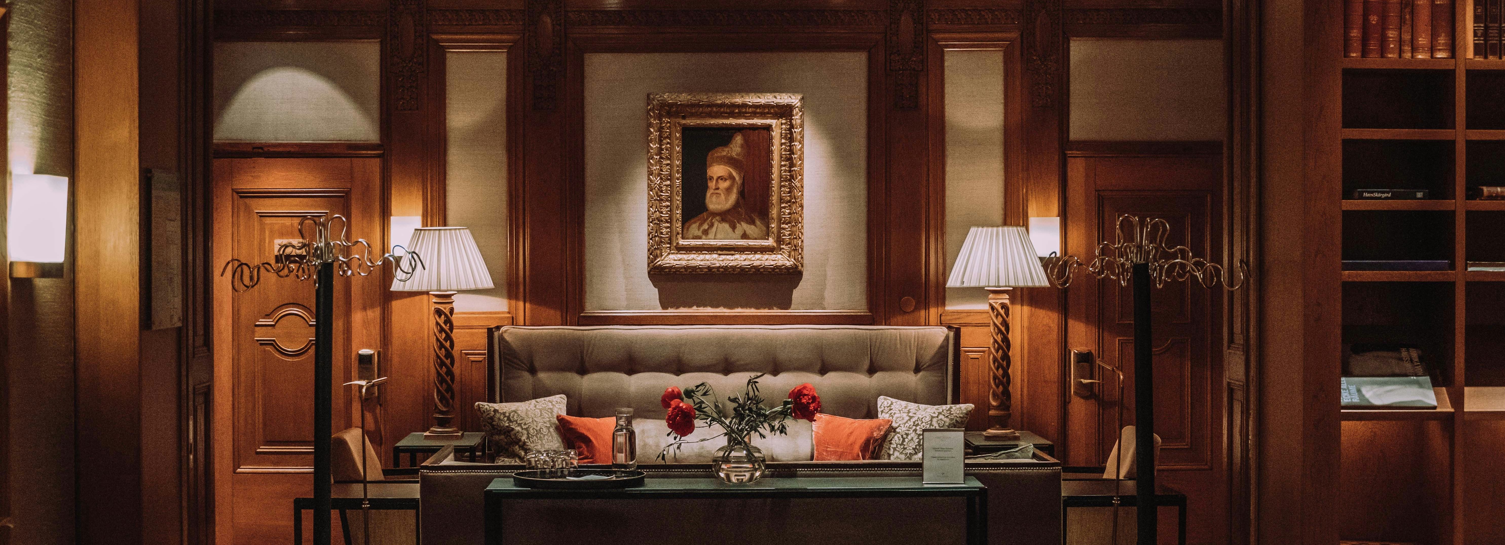 Elegant hotel lounge with vintage decor, a sofa, table, and portrait on the wall.