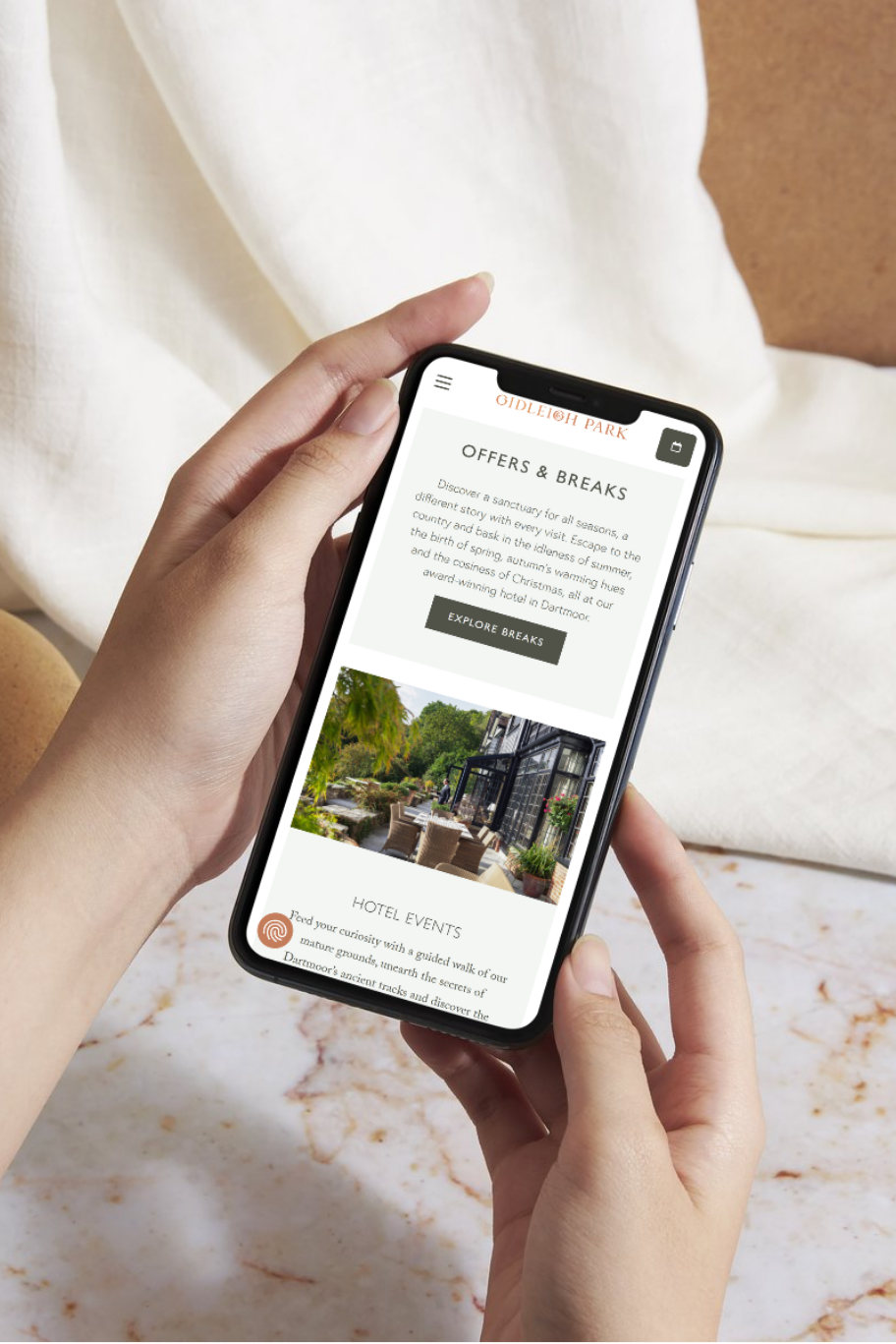 Person holding a smartphone displaying the Gidleigh Park mobile website