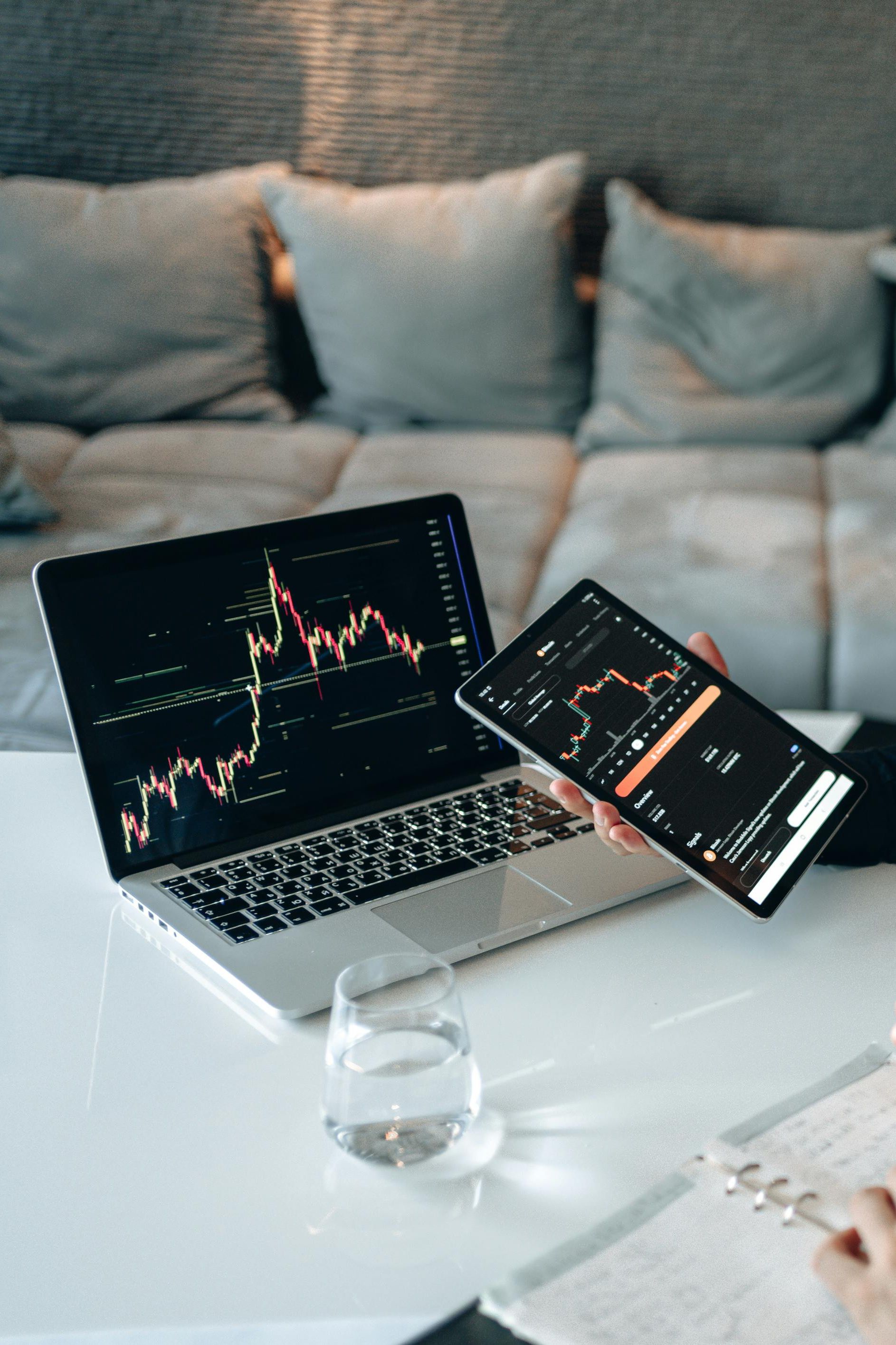Two men analyzing stock market data on a laptop and tablet at a desk.