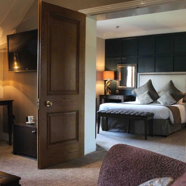 Luxurious hotel suite with a separate bedroom, plush furnishings, and warm lighting
