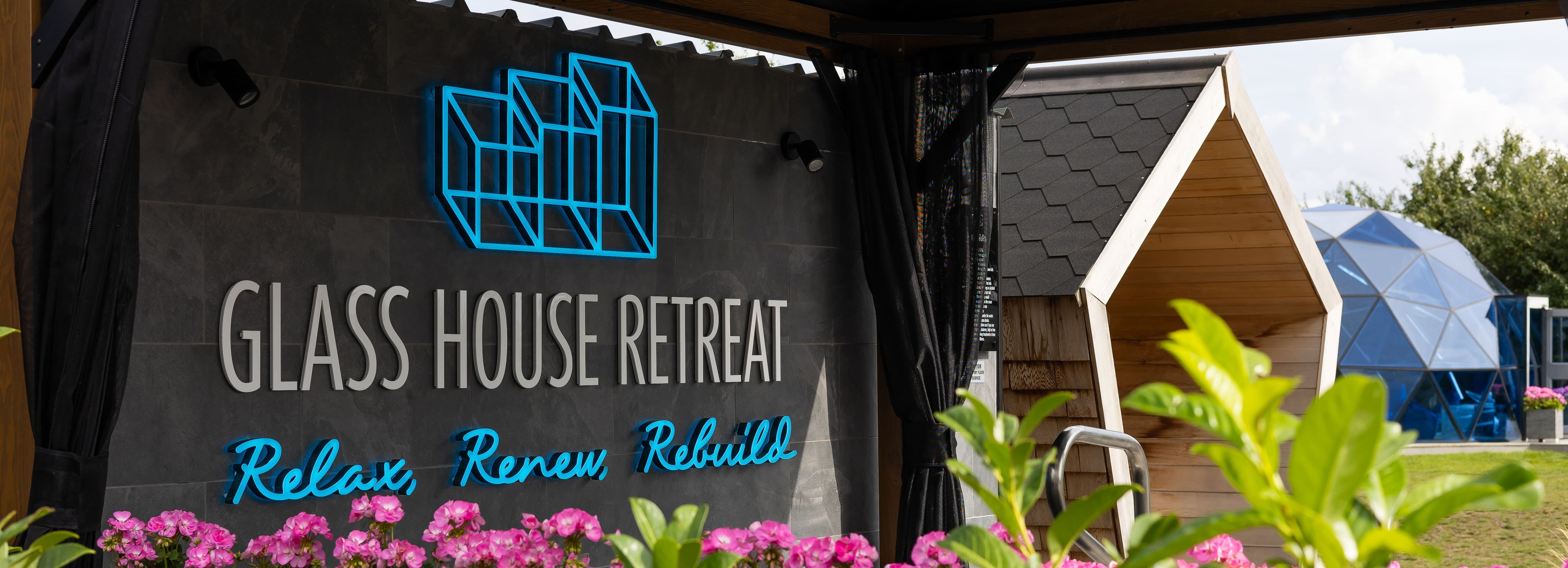 Glass House Retreat sign with flowers and outdoor seating area