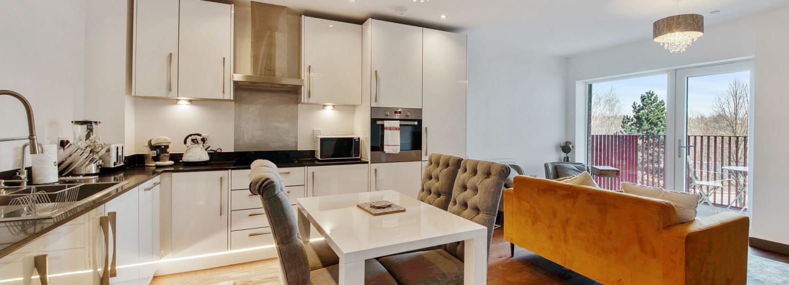 Modern open-plan kitchen and living room with large windows and balcony view