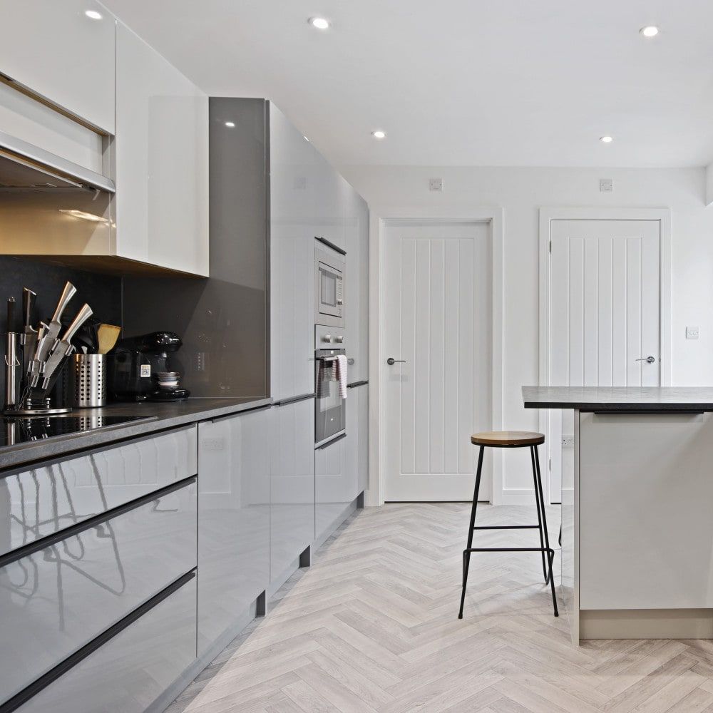 Modern kitchen with sleek white cabinets, black countertops, and bar stool