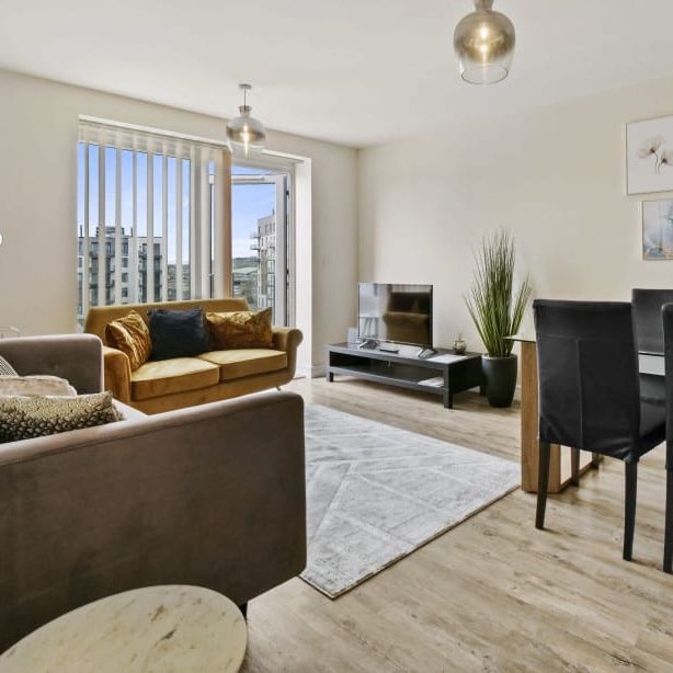 Modern living and dining area with sofas, a glass dining table, and wall art.
