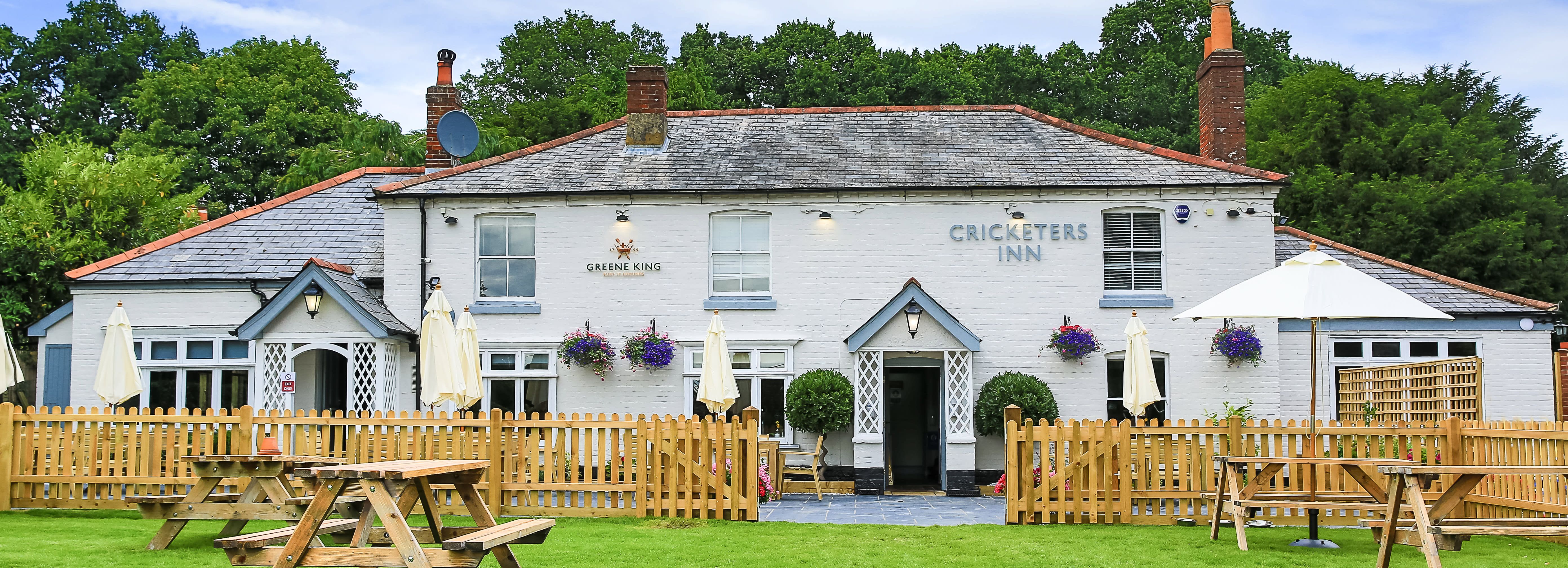 The Cricketers Inn, a traditional British pub with picnic tables and a fenced garden area