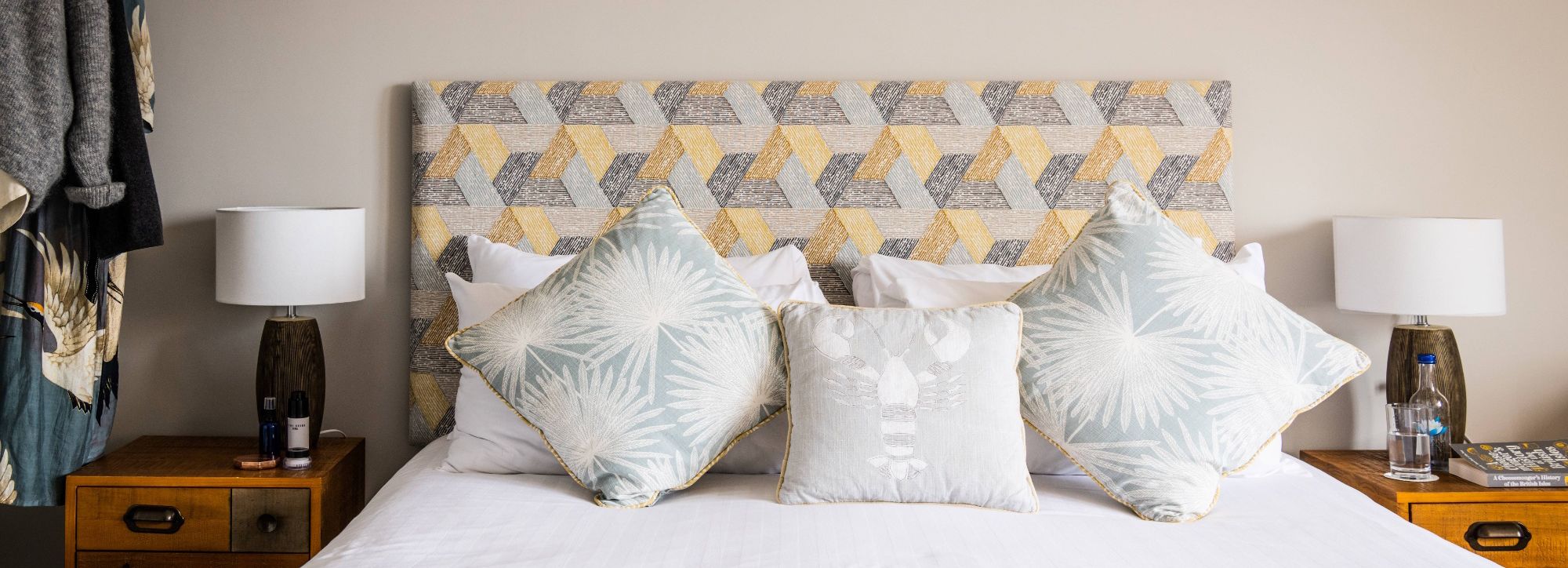 Modern bedroom with patterned headboard, decorative pillows, and bedside tables with lamps.