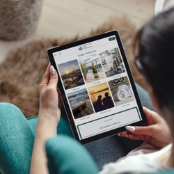 Person browsing lakeside holiday lodge listings on a tablet