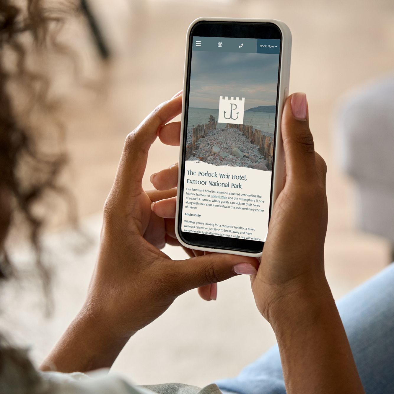 Person holding a smartphone displaying a hotel listing for The Porlock Weir Hotel in Exmoor National Park.