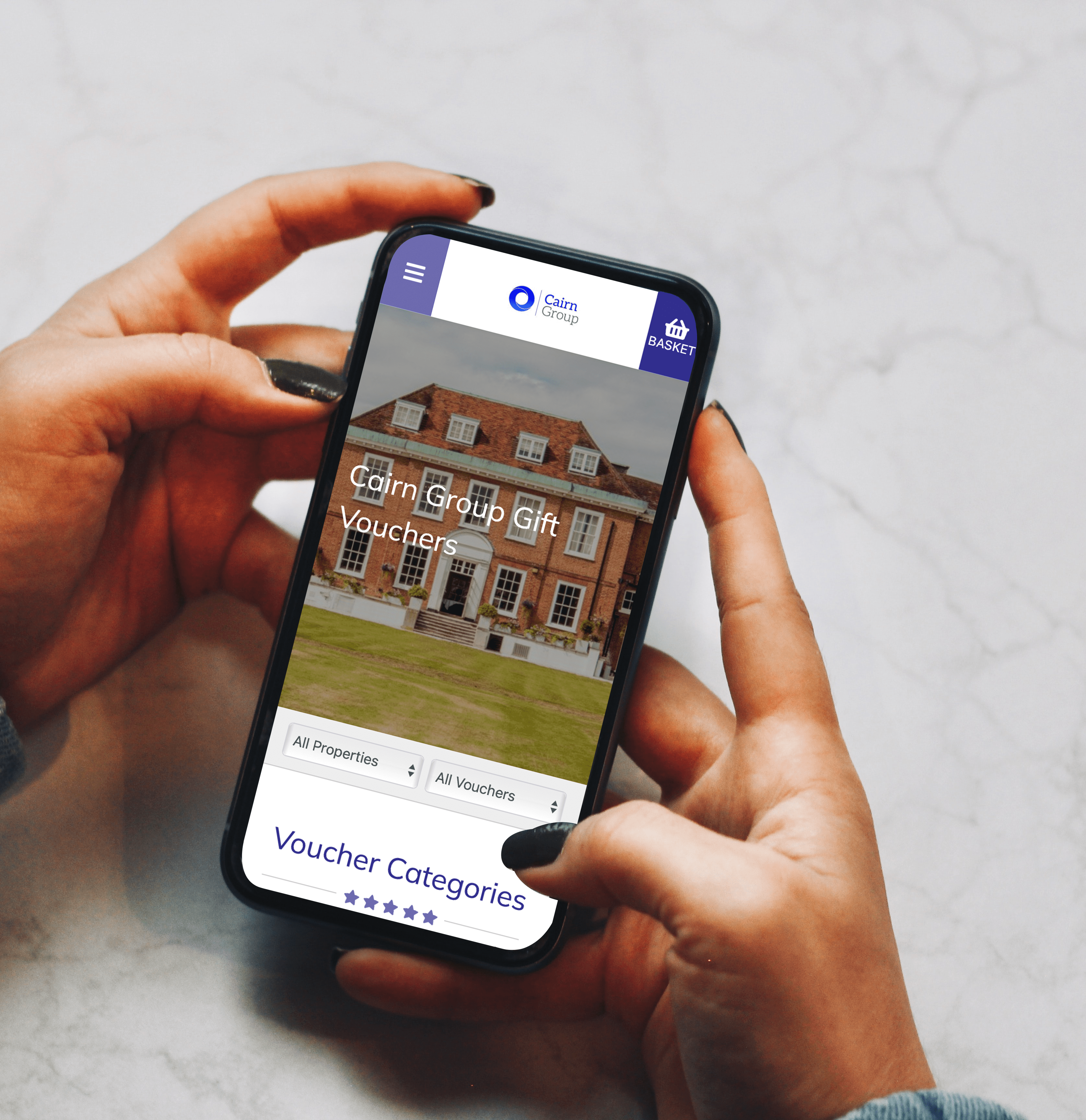 Person holding a smartphone displaying Cairn Group Gift Vouchers website