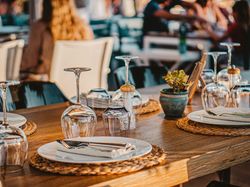 Close-up of a neatly set restaurant table with plates, cutlery, and upside-down wine glasses.