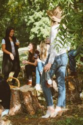 Group of friends enjoying drinks and talking outdoors while sitting on tree stumps