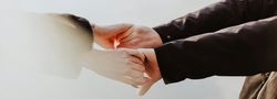 Two people gently holding hands outdoors