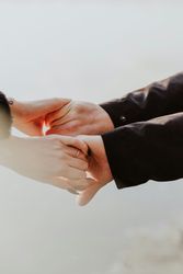 Two people gently holding hands outdoors