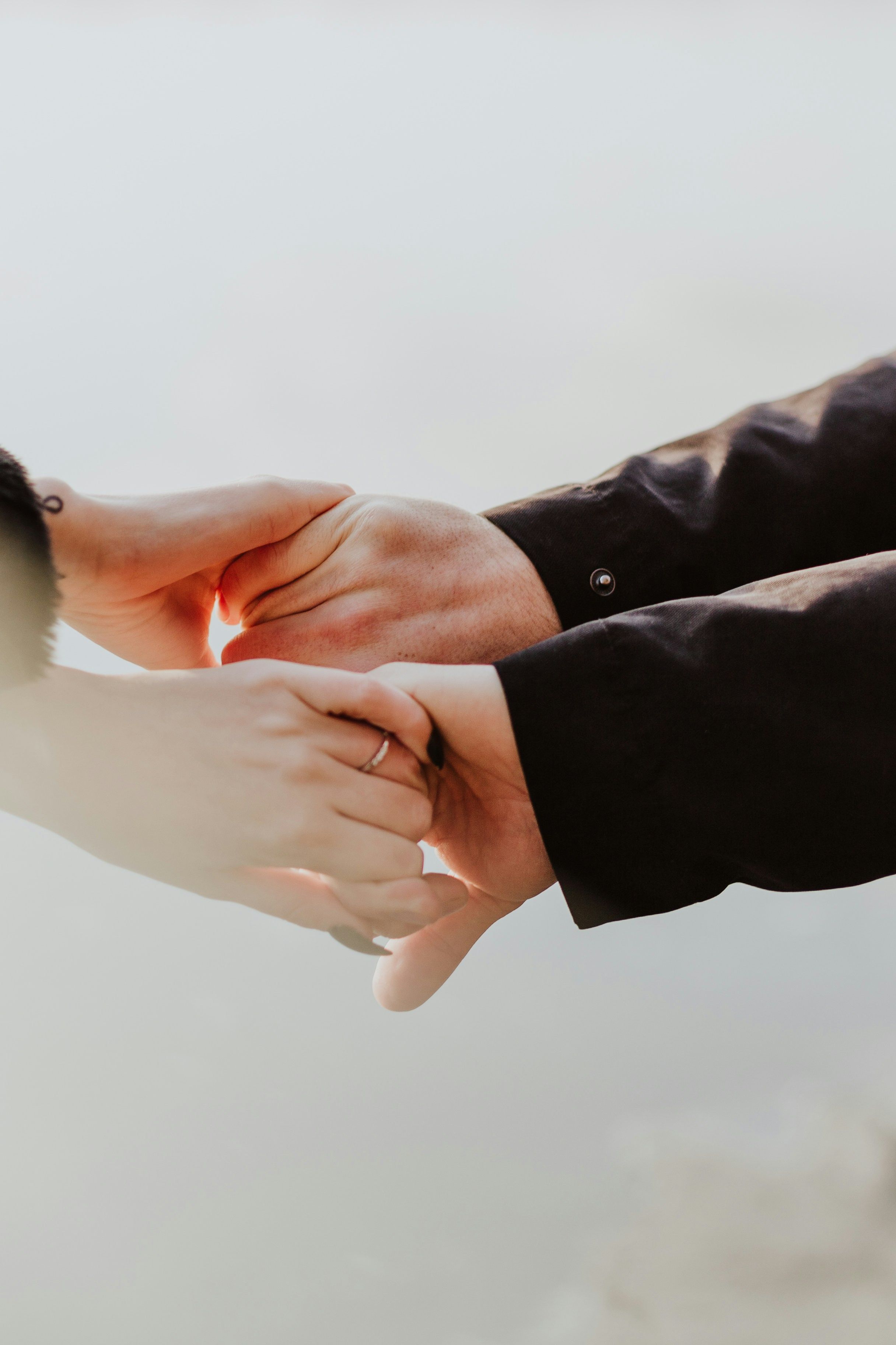 Two people gently holding hands outdoors
