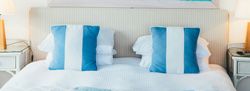 Coastal-themed bedroom with blue and white pillows and a large ocean painting above the bed
