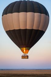 Hot air balloon flying over a plain at sunrise or sunset