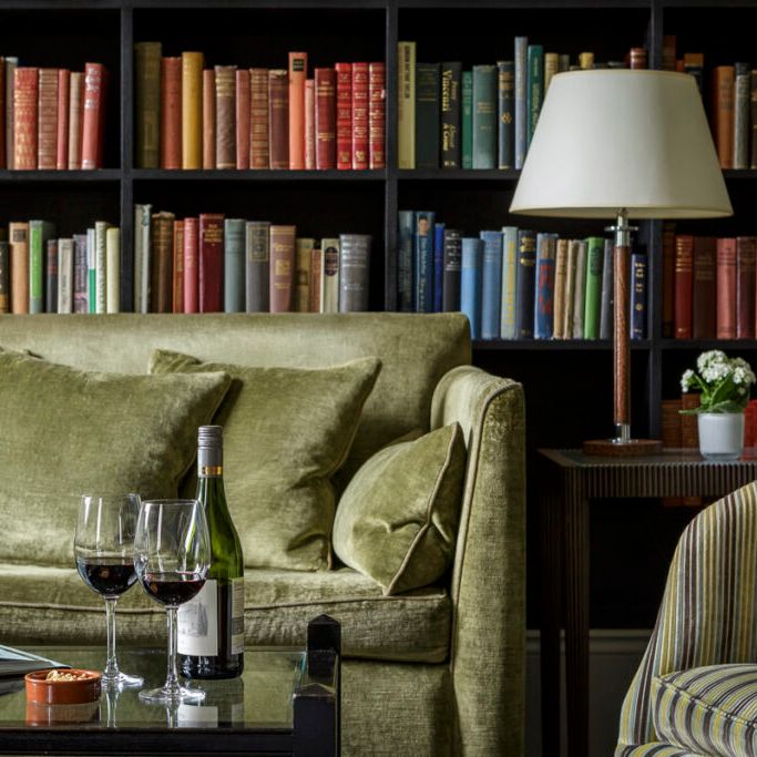 Cozy living room with olive green sofa, bookshelves, and wine glasses on a coffee table