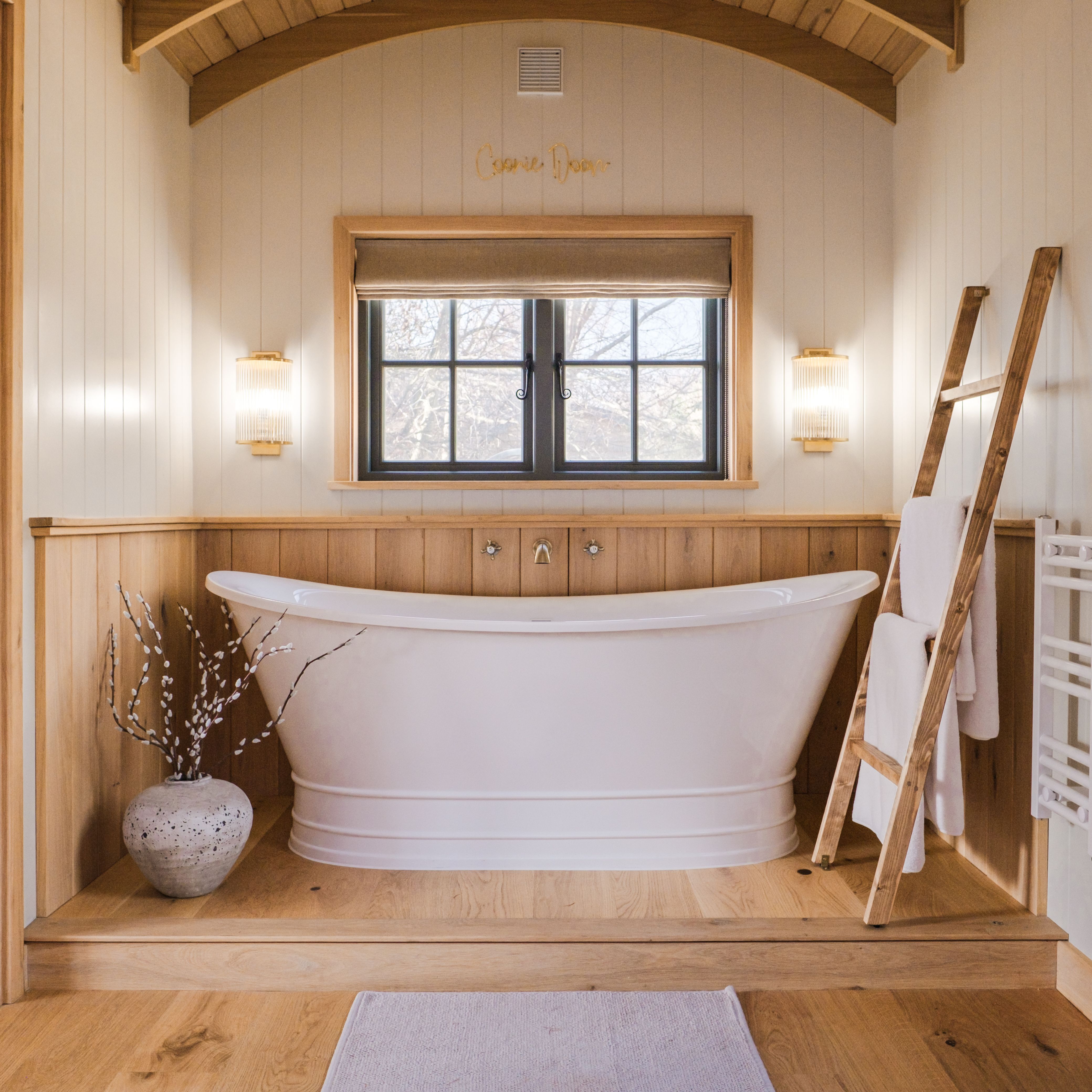 Modern bathroom with freestanding white tub, wooden accents, and large window
