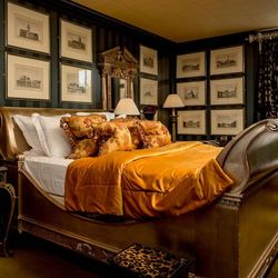 Luxurious bedroom with ornate gold bed and frames, opulent bedding, and classic decor.