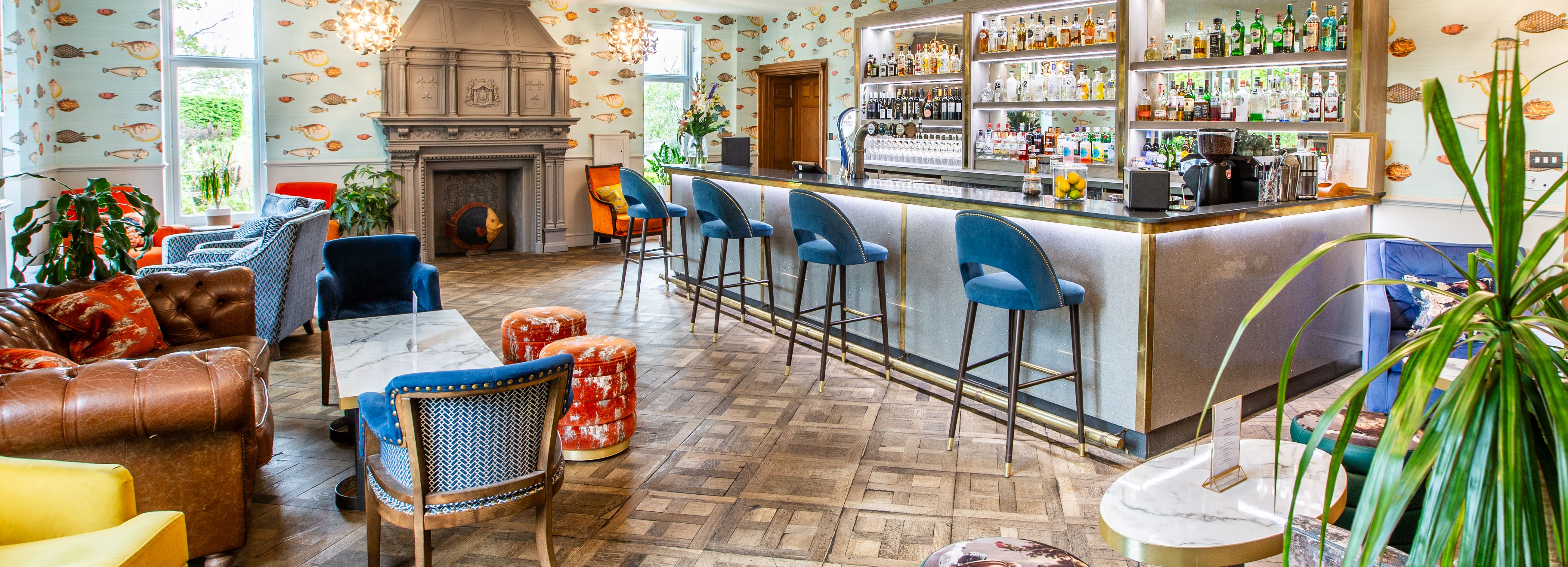 Colorful and stylish bar lounge with a variety of seating, a fireplace, and a well-stocked bar.