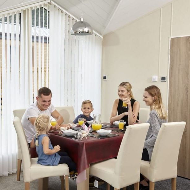 Family sitting around a dining table inside a modern home, enjoying breakfast together