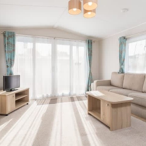 Bright modern living room with beige sofa, wooden furniture, and large windows with teal curtains