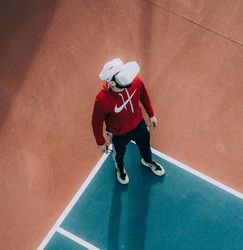 Person wearing a red hoodie and virtual reality headset standing on a sports court