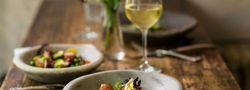 A gourmet meal served in a rustic setting with a glass of white wine