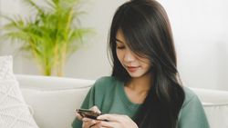 Woman sitting on a couch looking at her smartphone