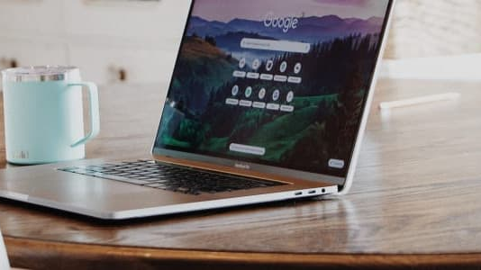 Laptop on wooden table with light blue mug