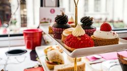 Assorted pastries and sandwiches arranged on a tiered tray inside a cafe or restaurant
