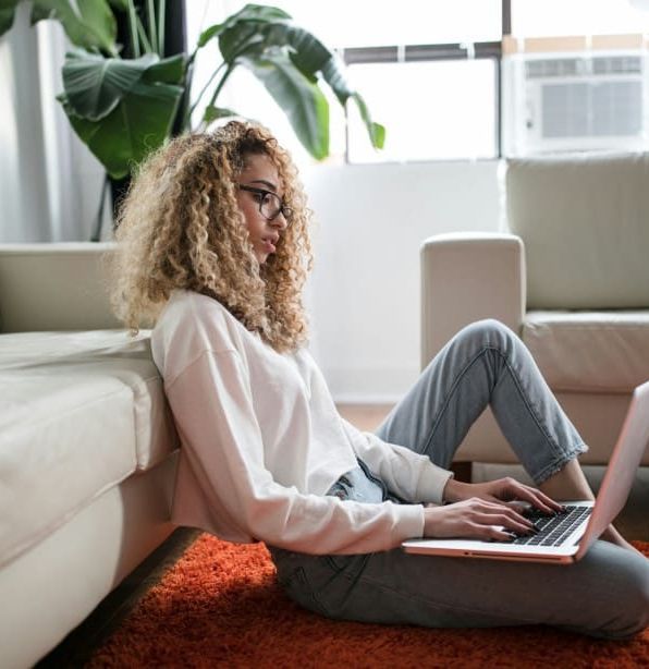 Woman sitting on floor with laptop in living room