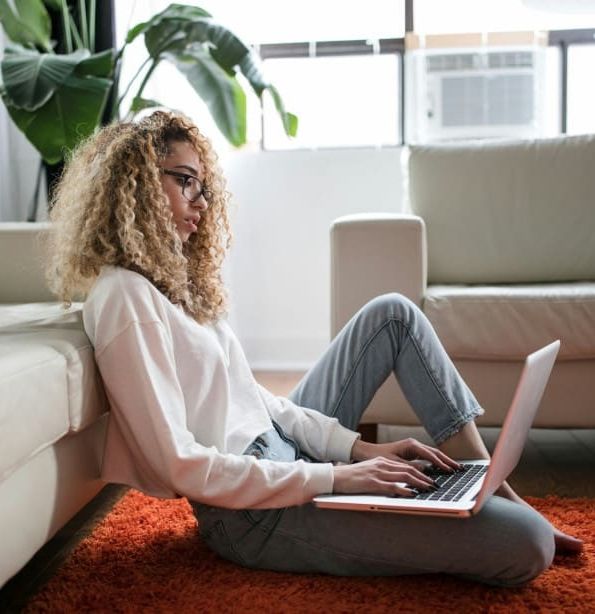 Woman sitting on floor with laptop in living room