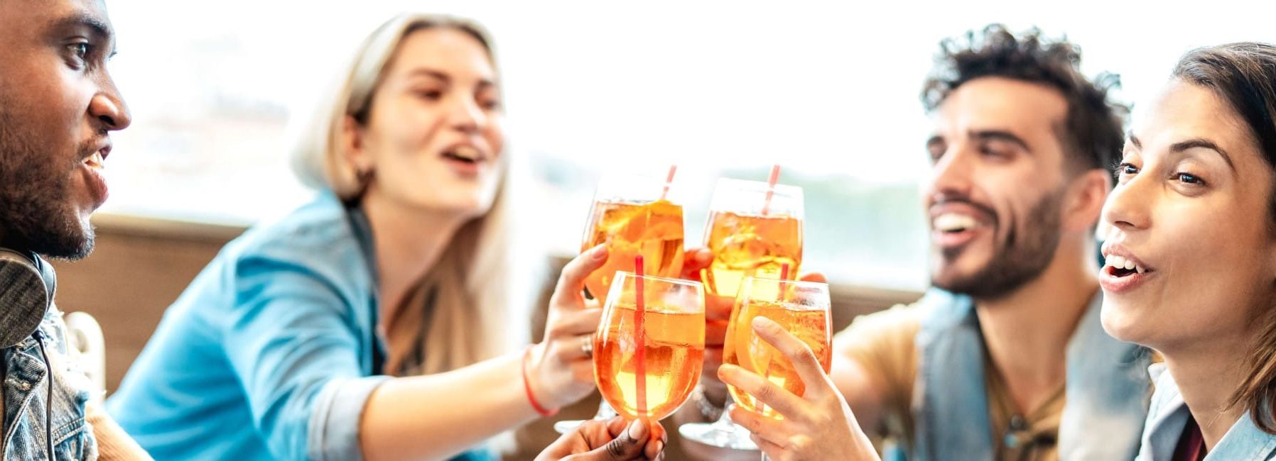 Group of friends clinking glasses in a toast while sitting together at a table.