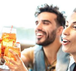Group of friends clinking glasses in a toast while sitting together at a table.
