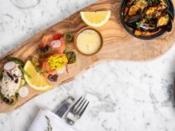 Elegant seafood appetizer platter on a wooden board with a glass of white wine