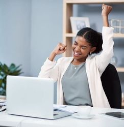 Woman celebrating success at her desk in a modern office