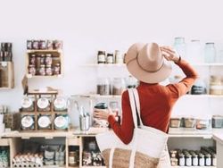 Person wearing a hat and holding a reusable bag shopping in a zero waste store