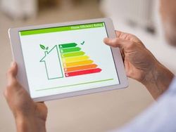Person holding a tablet displaying a house energy efficiency rating chart