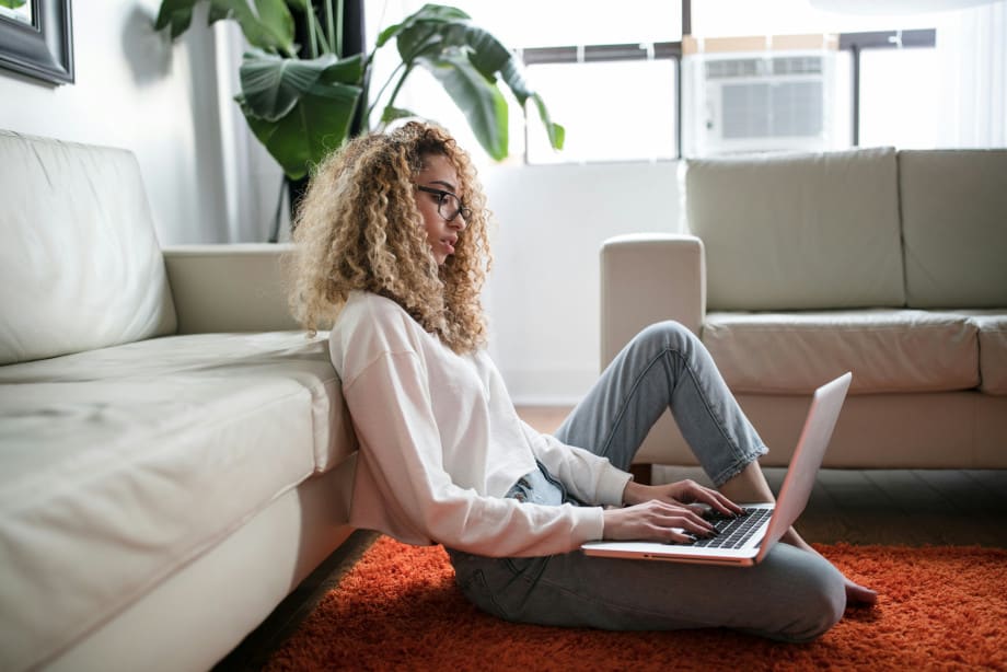 Lady sitting on living room floor on laptop