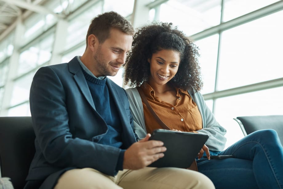 2 people sat on a sofa looking at a tablet