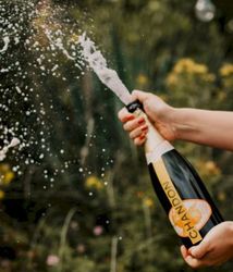person popping a bottle of Chandon champagne outdoors