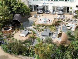 Outdoor spa area with hot tub, sun loungers, garden seating, and lush greenery at St Michaels.
