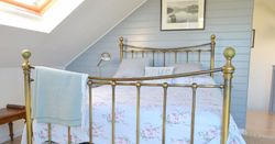 Brass bed with floral blanket in a cozy attic bedroom