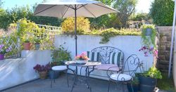 Cozy outdoor patio with wrought iron furniture, umbrella, and potted plants
