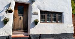 Traditional whitewashed cottage with thatched roof and wooden door