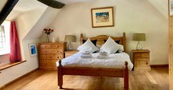 Cozy bedroom with wooden furniture, a double bed, and natural lighting.
