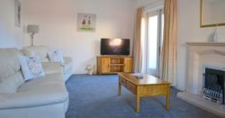 Bright living room with cream sofa, TV, fireplace, and wooden furniture.