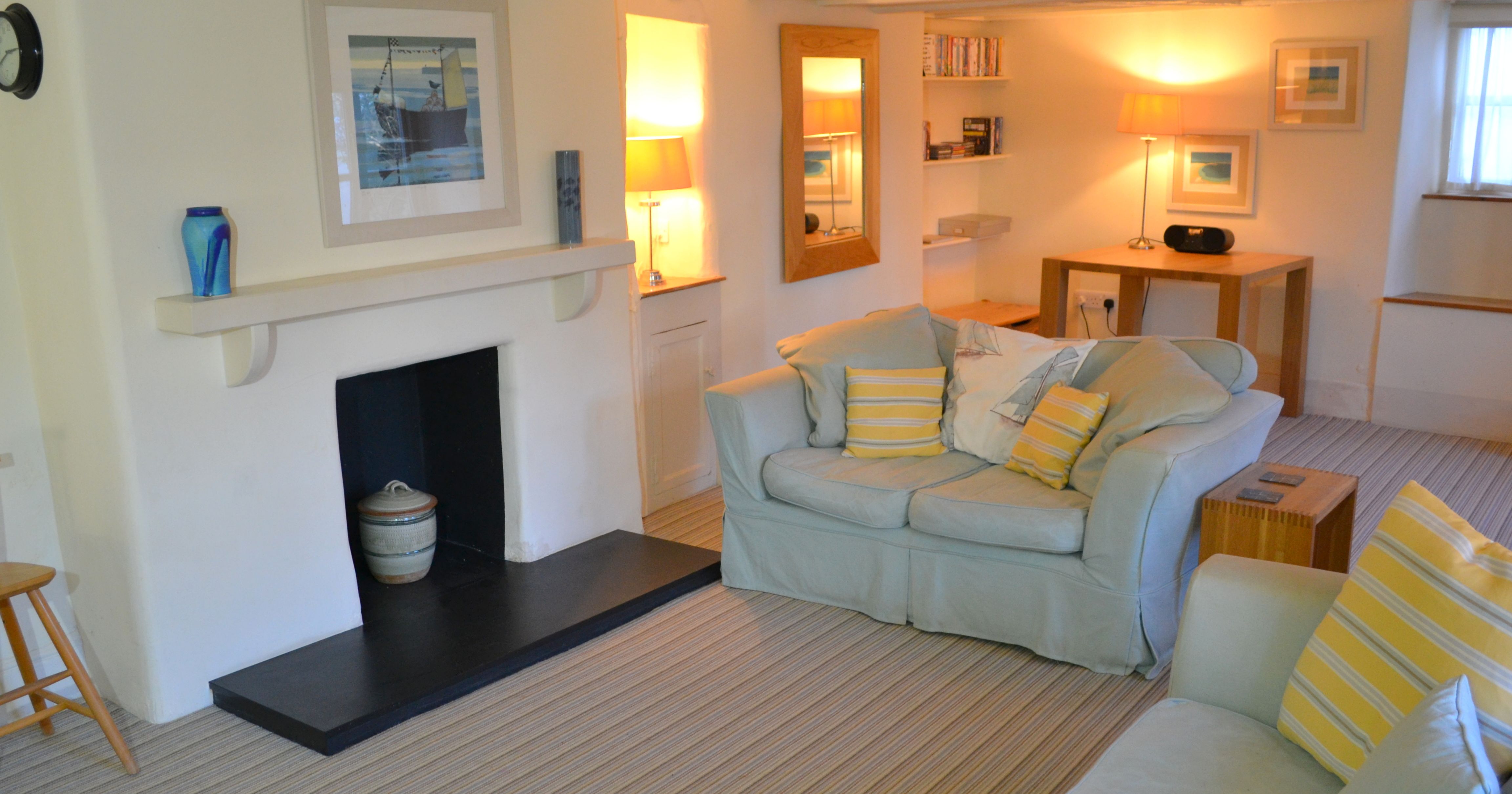 Cozy living room with light-colored sofas, striped cushions, and a fireplace